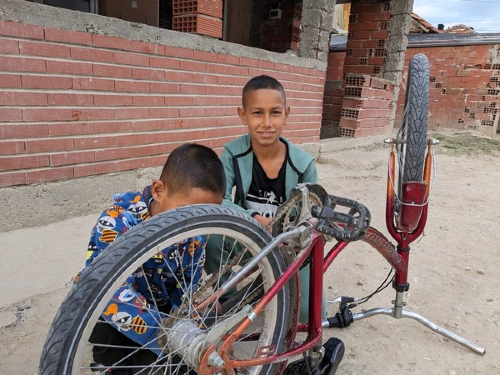 David works on his bike with a  friend